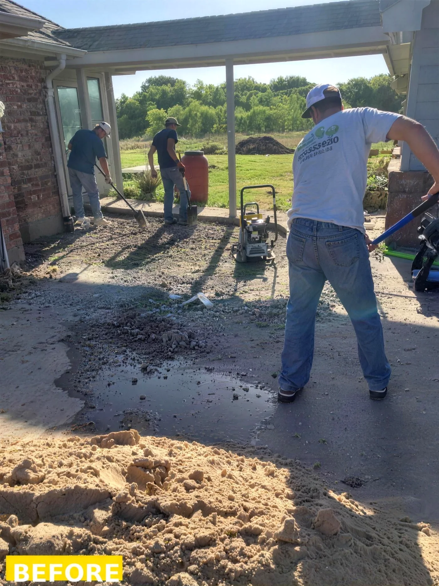 Same patio area before hardscaping, rough gravel base and crew prepping the site